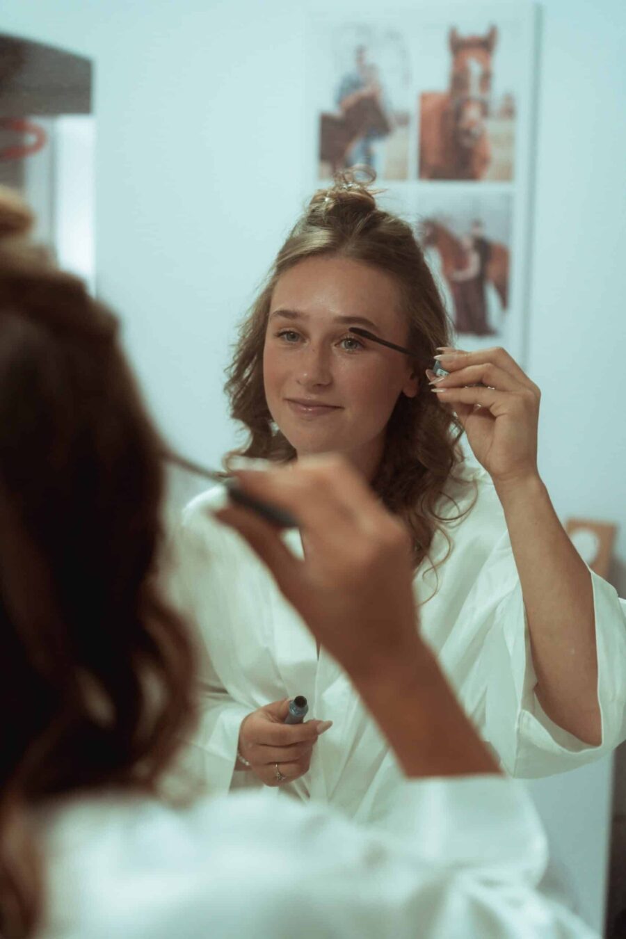 Braut schminkt sich vor der Hochzeit im Spiegel