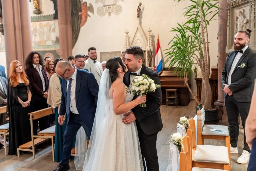 Brautpaar küsst sich im festlichen Kirchensaal
