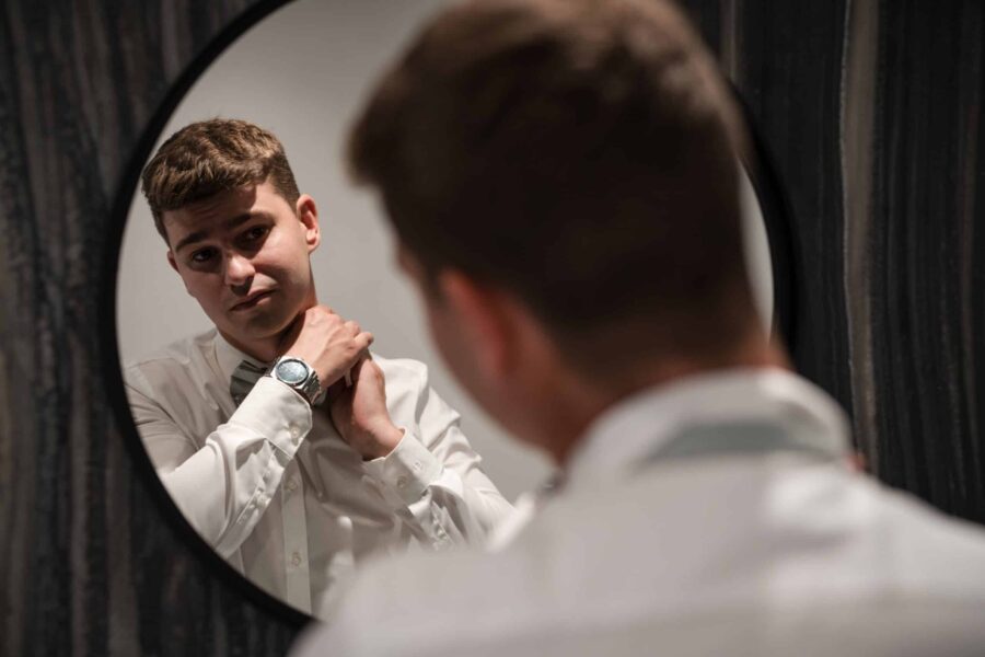 Bräutigam richtet Fliege im Spiegel