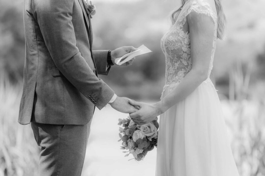 Brautpaar hält Hände bei Trauzeremonie im Freien