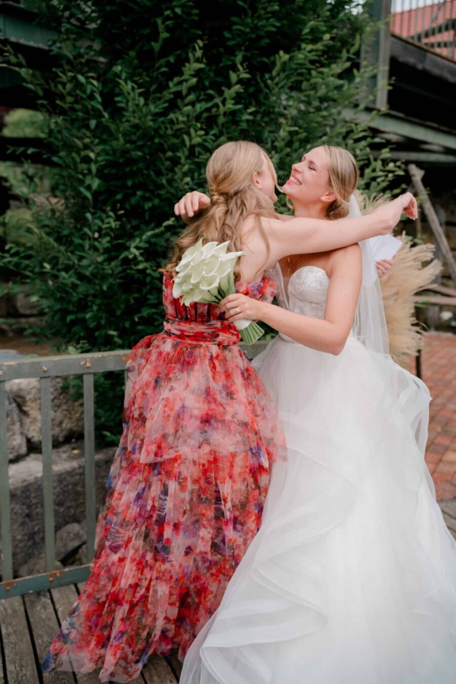 Braut umarmt Gast mit Blumenstrauß.