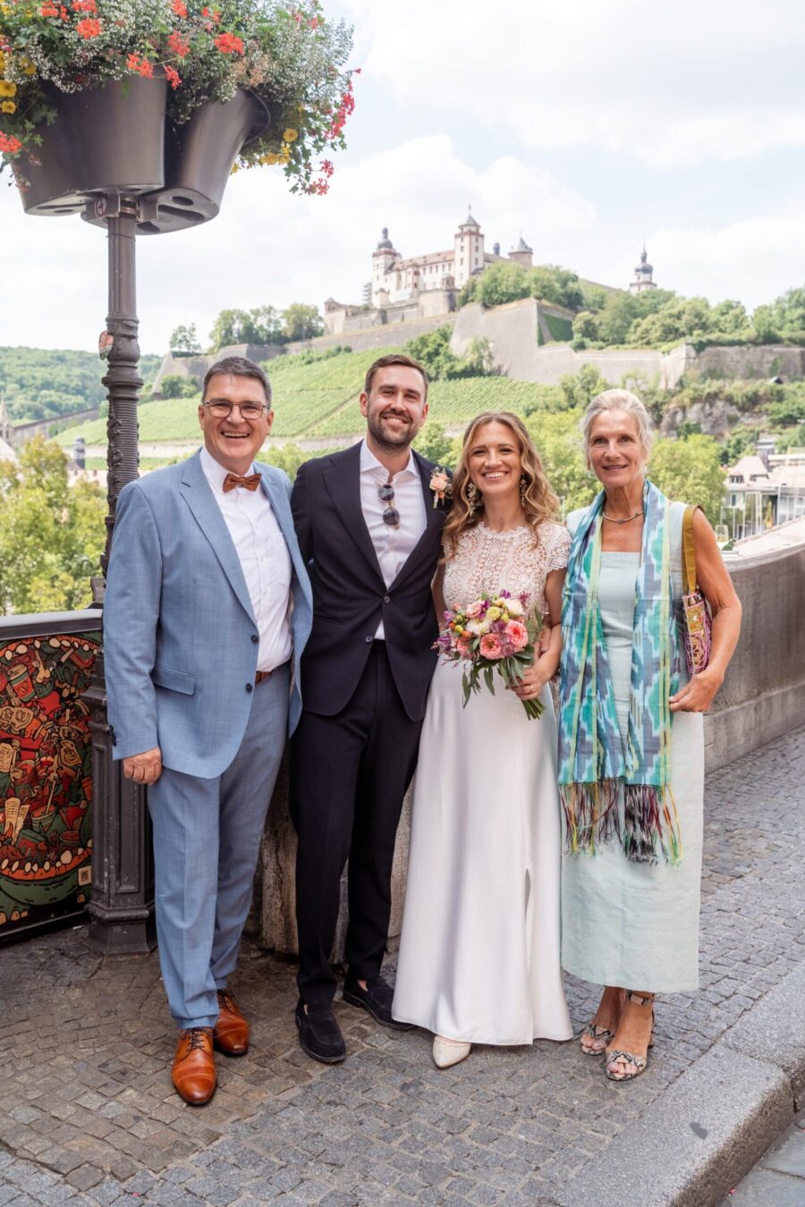 Hochzeit Steinburg Würzburg | Editorial Style & Party | Florian Knusper 5 Brautpaar mit Gästen vor Festung im Sommer