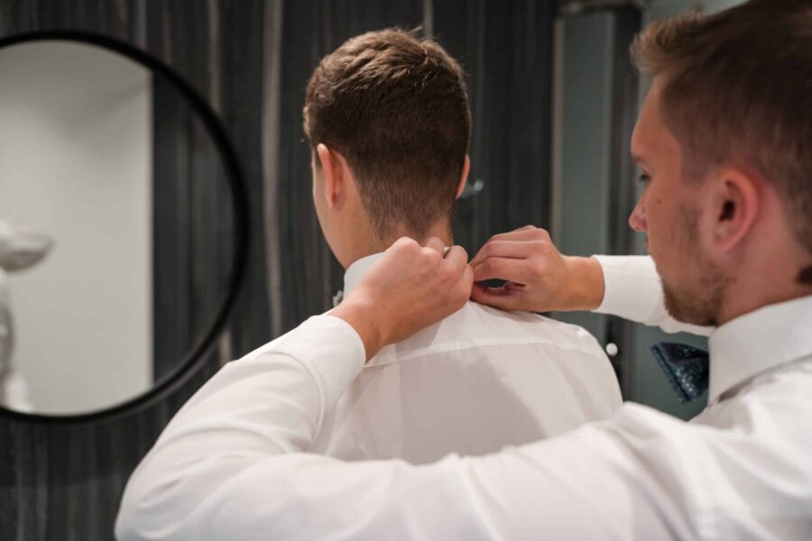 Mann richtet Krawatte am Hochzeitstag im Ankleidezimmer.