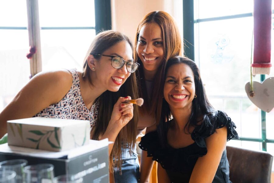 Drei lachende Frauen bei Hochzeitsvorbereitungen.