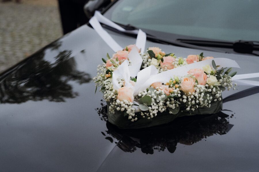 Blumenherz auf Motorhaube eines Hochzeitsautos