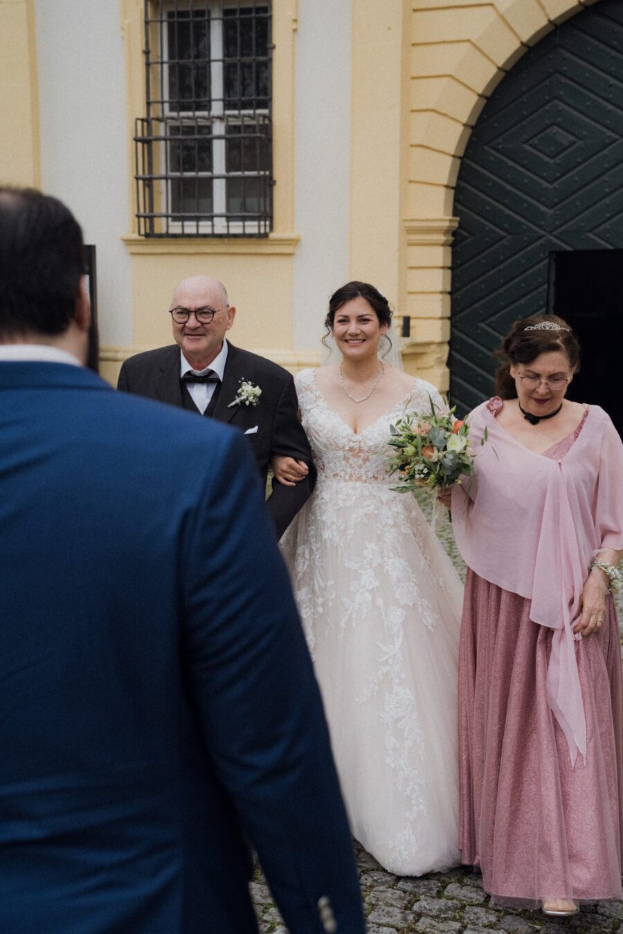 Braut mit Eltern vor historischem Gebäude