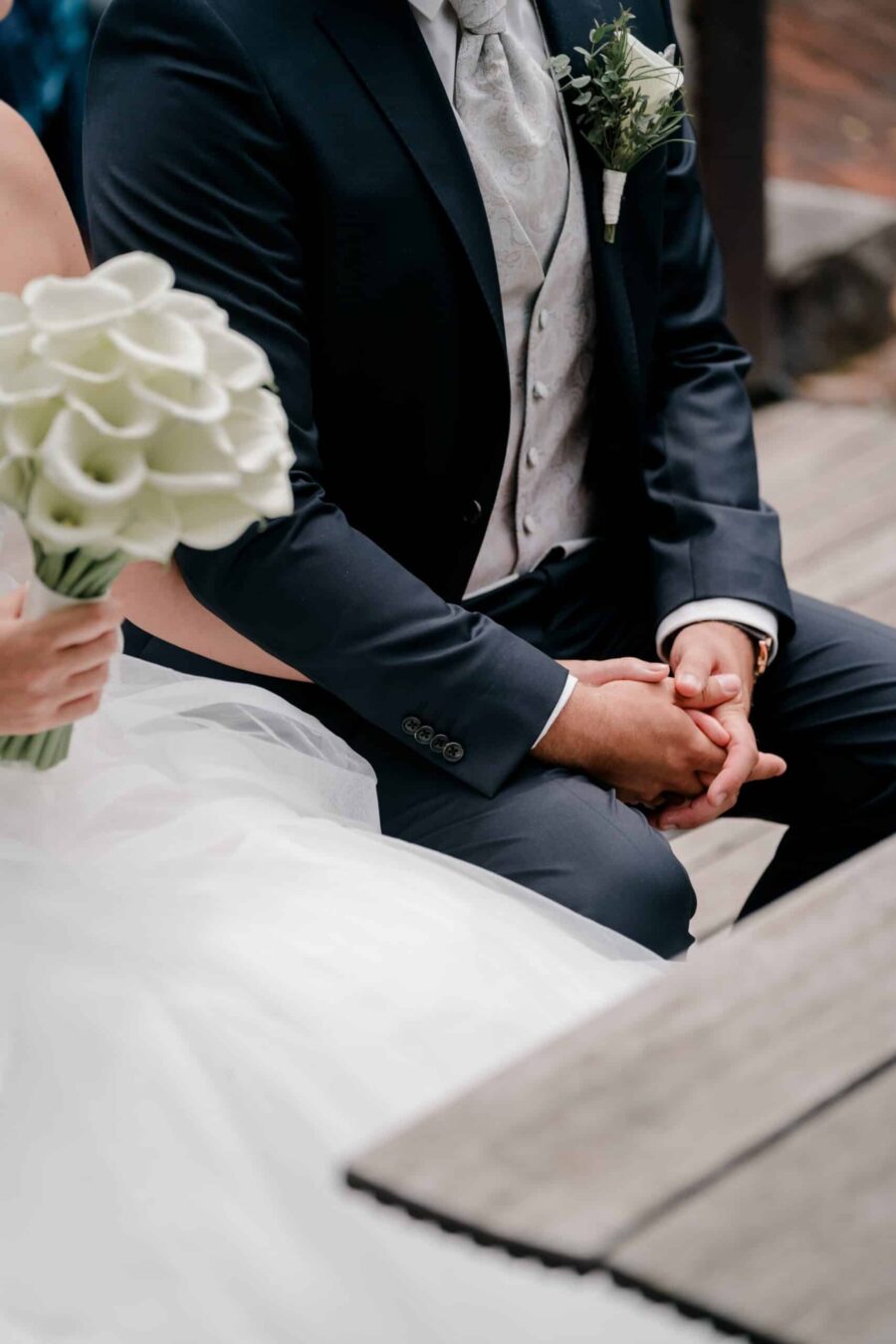 Brautpaar hält Händchen mit Blumenstrauß