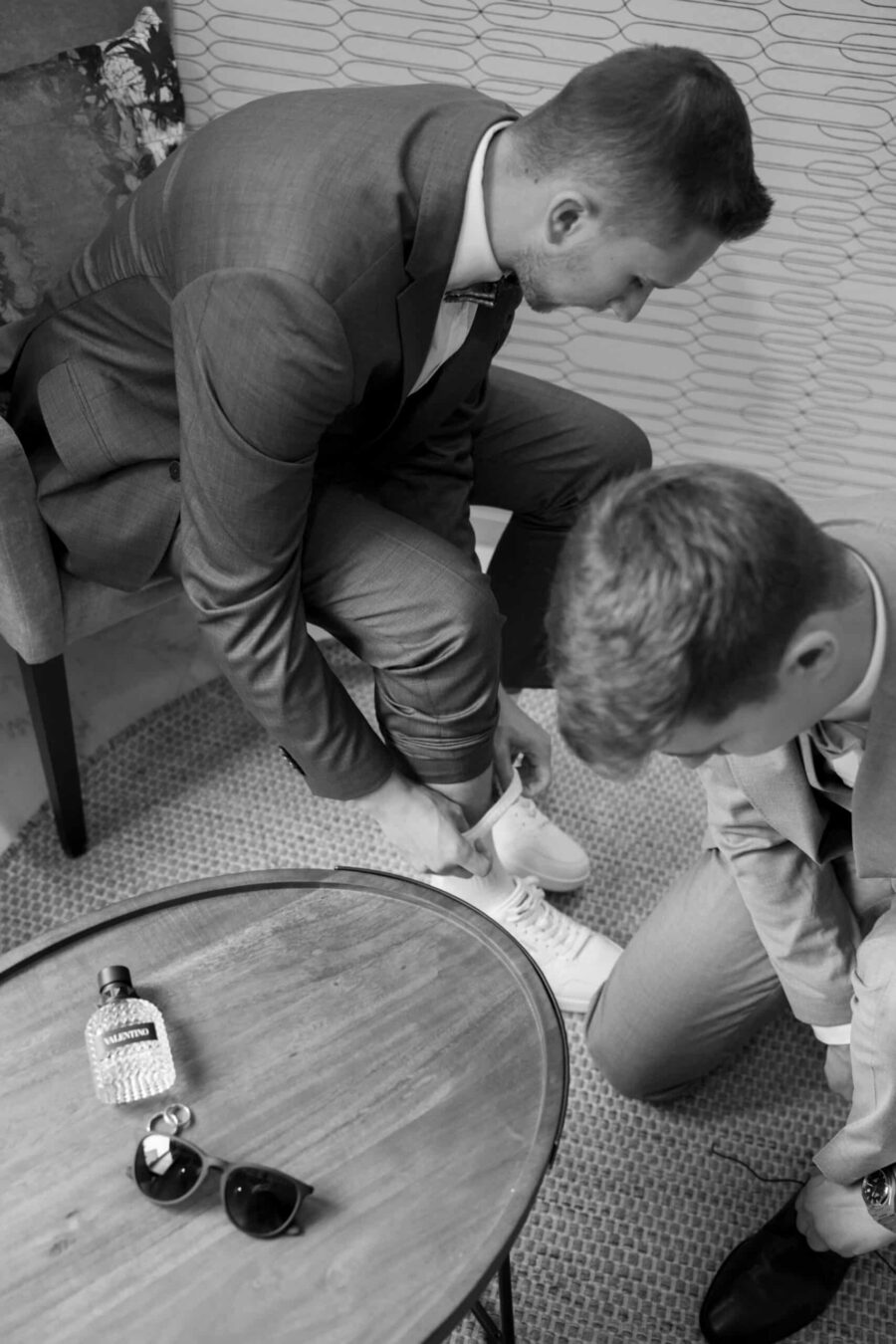 Männer helfen sich beim Anziehen der Hochzeitsschuhe