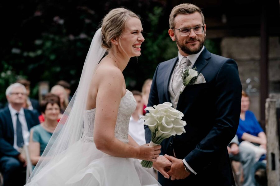 Brautpaar lächelt während Trauung im Freien