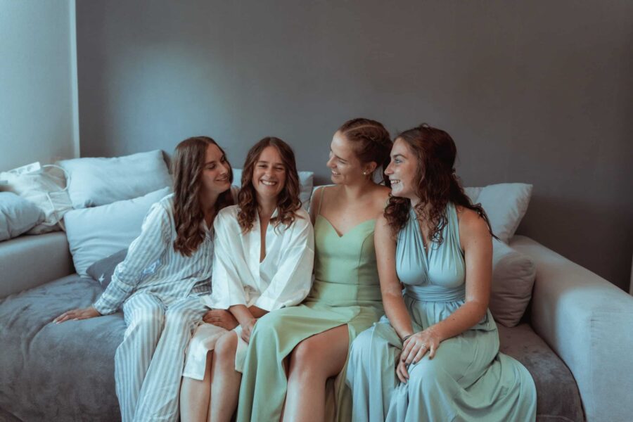 Brautjungfern lächelnd auf Sofa im Ankleidezimmer