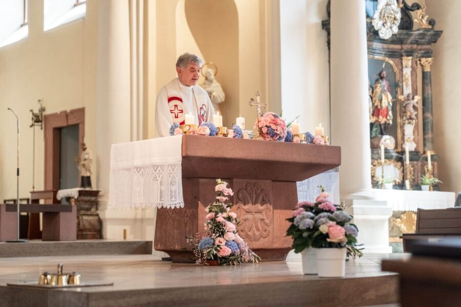 Priester im Gottesdienst am geschmückten Altar in Kirche