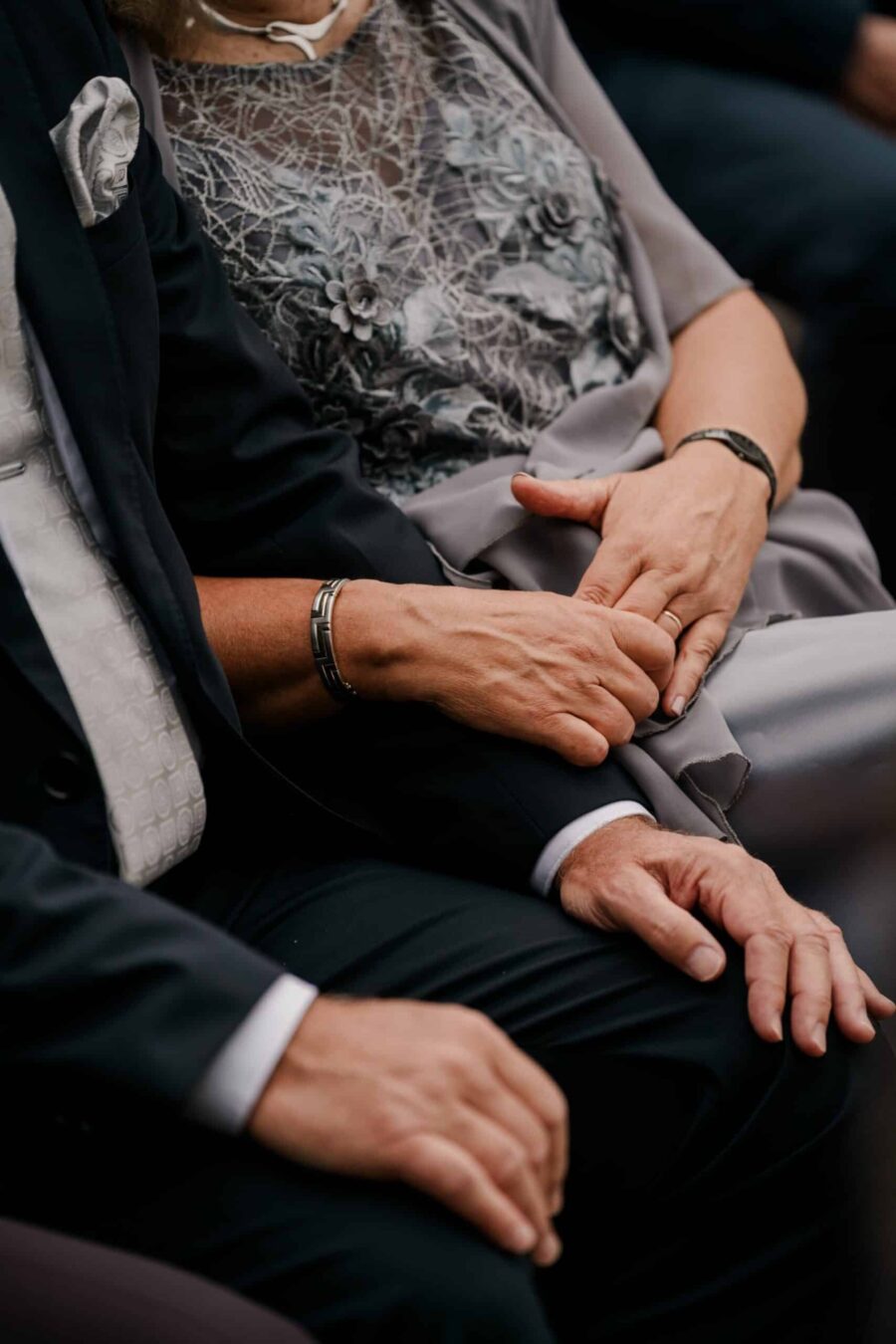 Hände von Hochzeitsgästen in feierlicher Kleidung