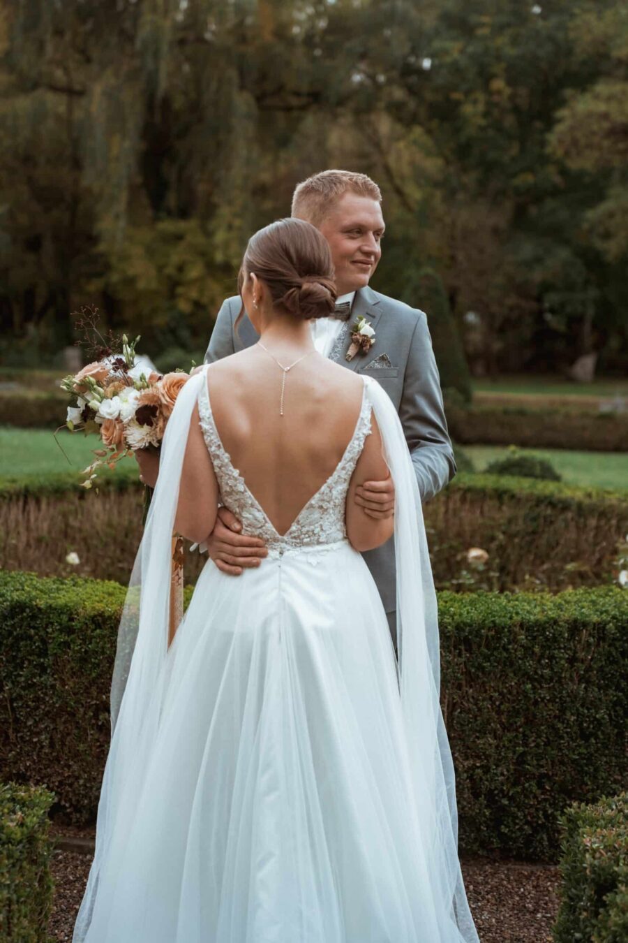 Brautpaar im Garten mit Blumenstrauß im Herbst