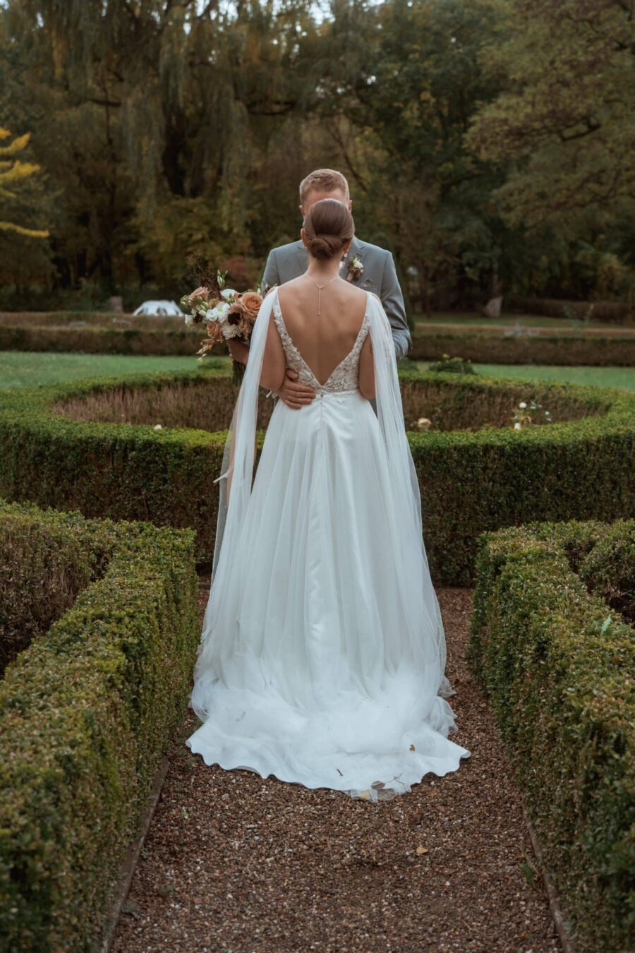 Brautpaar im Garten umarmt sich romantisch