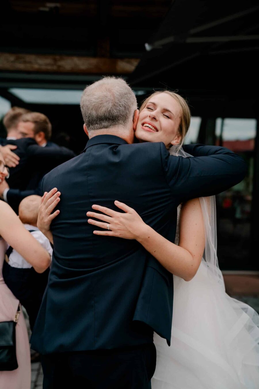 Braut umarmt Gast bei Hochzeitsfeier im Freien