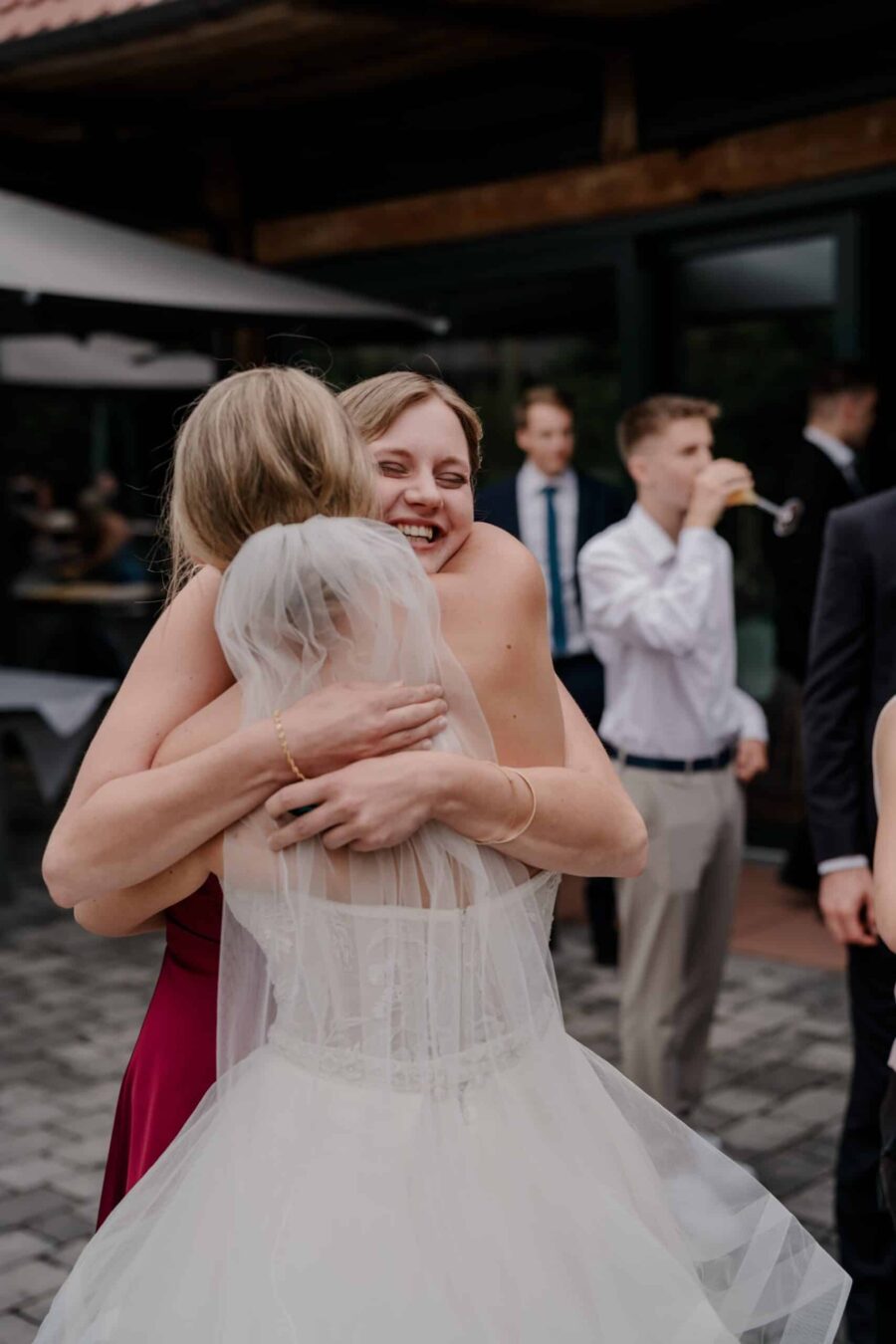 Braut umarmt Gast bei Hochzeitsfeier draußen.