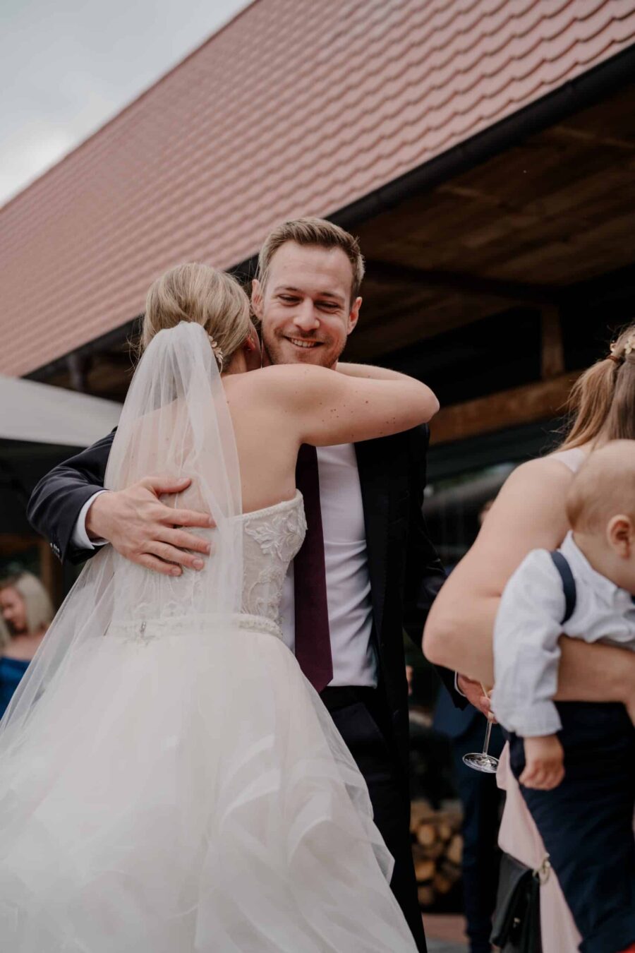 Bräutigam umarmt Braut im Freien bei Hochzeit