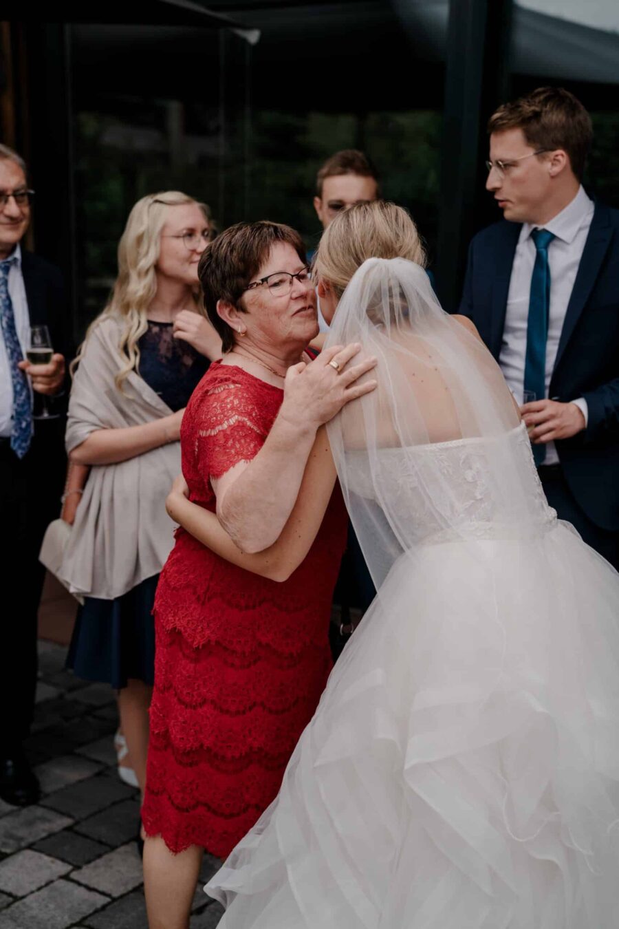 Braut umarmt Gast bei Hochzeitsfeier im Freien