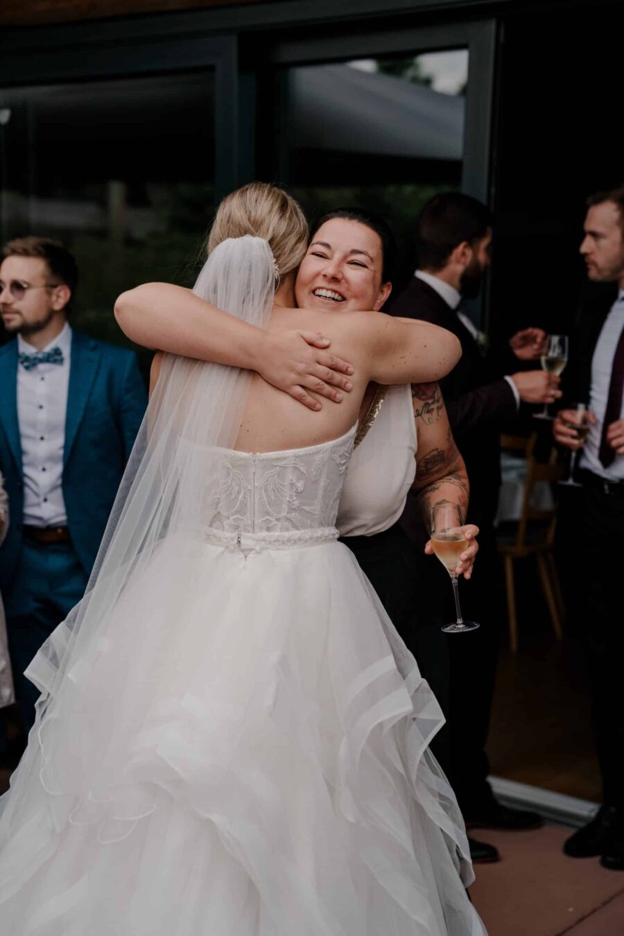 Umarmung bei Hochzeitsfeier mit Sektgläsern