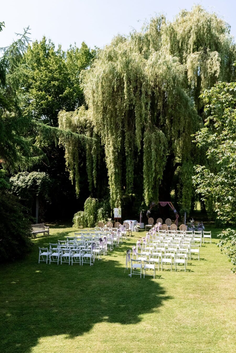 Gartenhochzeit mit Stuhlreihen unter großen Bäumen, Hofgut Hünersdorff