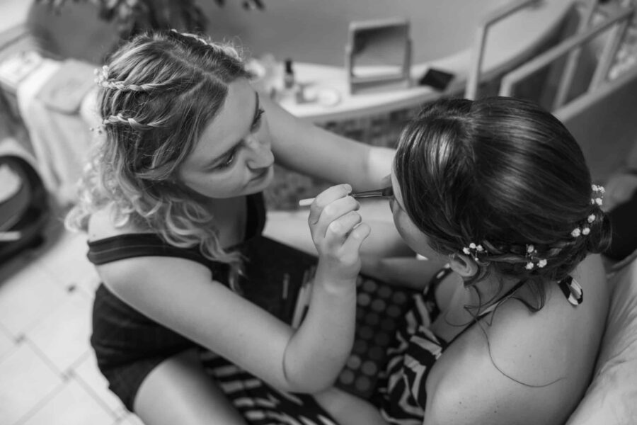 Brautjungfer schminkt Braut vor Hochzeit.