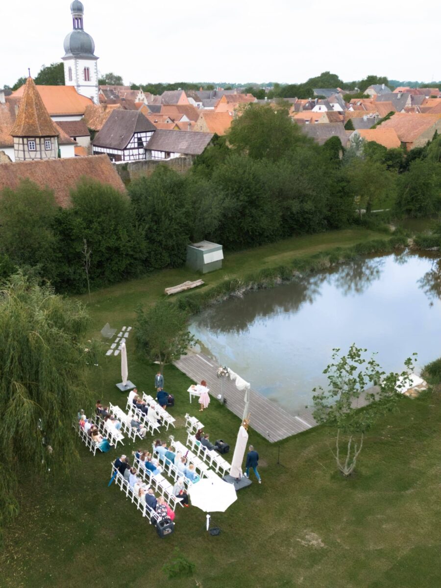Hochzeitszeremonie am See mit Gästen und Pavillon