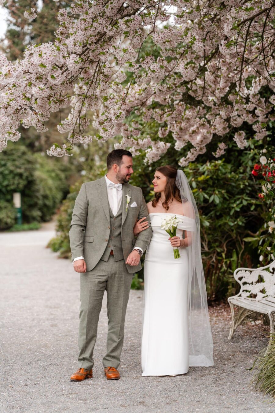 Hochzeit Insel Mainau Bodensee – Heiraten am Bodensee 15 Brautpaar spaziert im Garten unter Frühlingsblüten