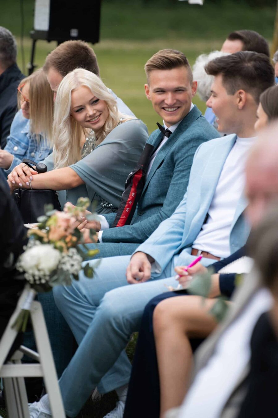 Gäste sitzen lächelnd bei freier Trauung im Garten