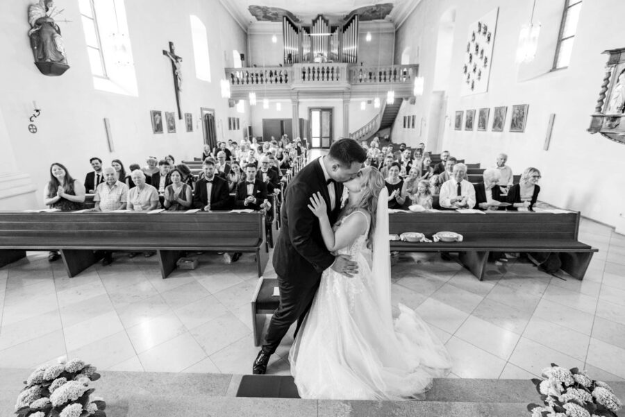 Brautpaar küsst sich vor Gästen in der Kirche