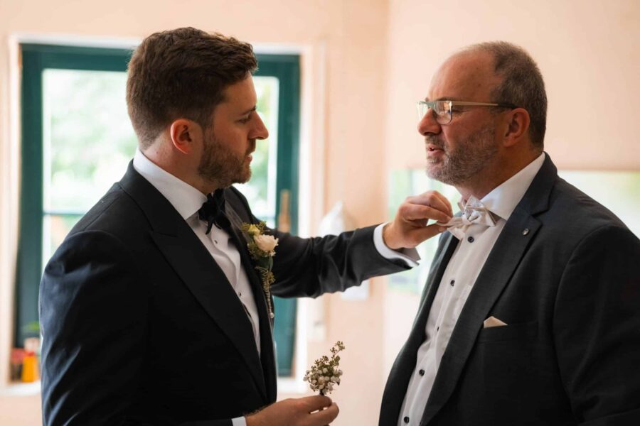 Bräutigam richtet Fliege des Vaters