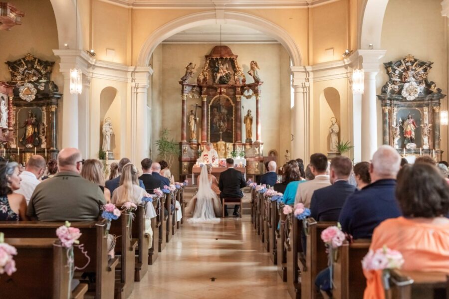 Kirchliche Trauung mit Brautpaar und Gästen.