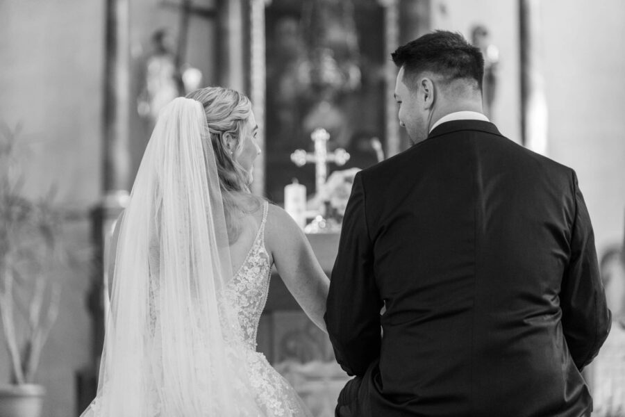 Brautpaar sitzt vor Altar in der Kirche.