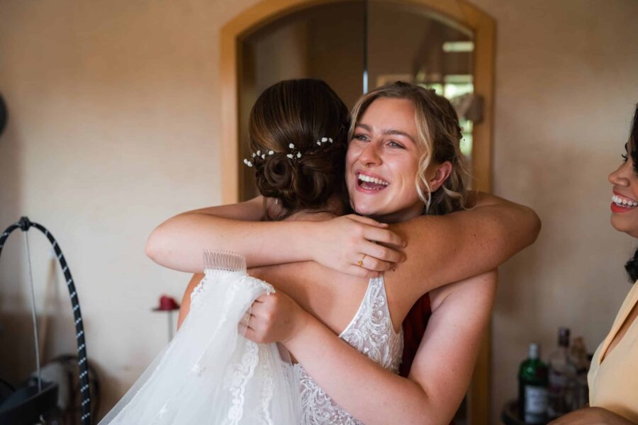 Braut umarmt Freundin im Vorbereitungsraum​​