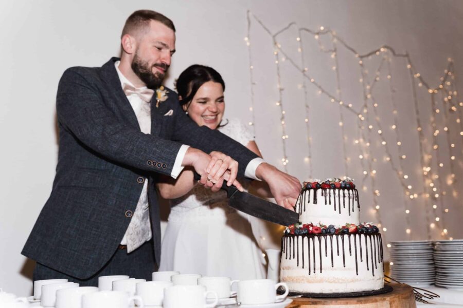 Brautpaar schneidet Hochzeitstorte an.