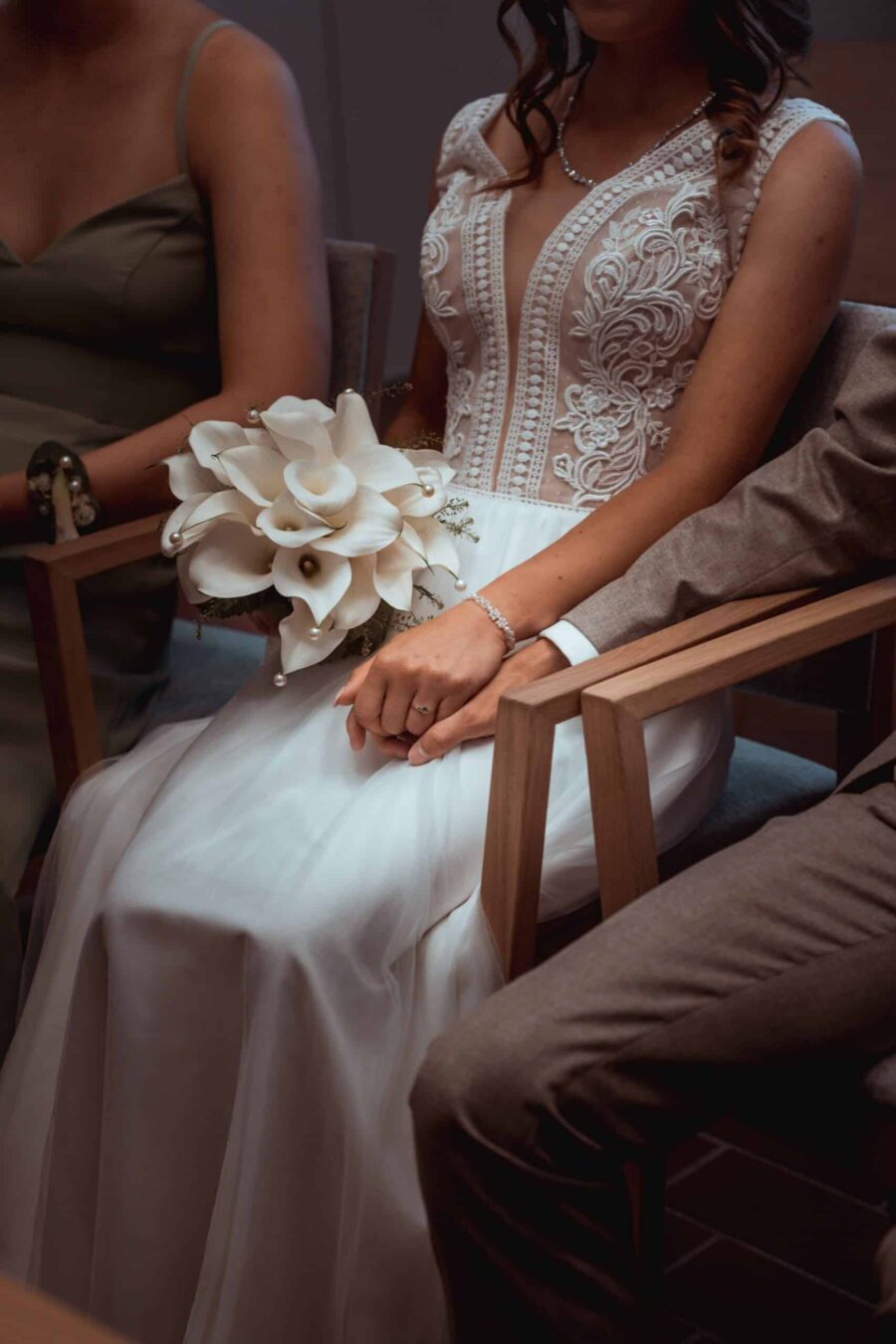 Brautpaar hält Hände mit Blumenstrauß im Innenraum