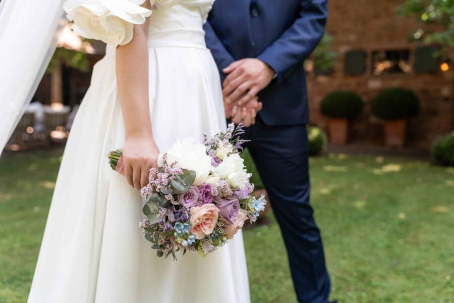 Braut hält Blumenstrauß im Garten, Hofgut Hünersdorff