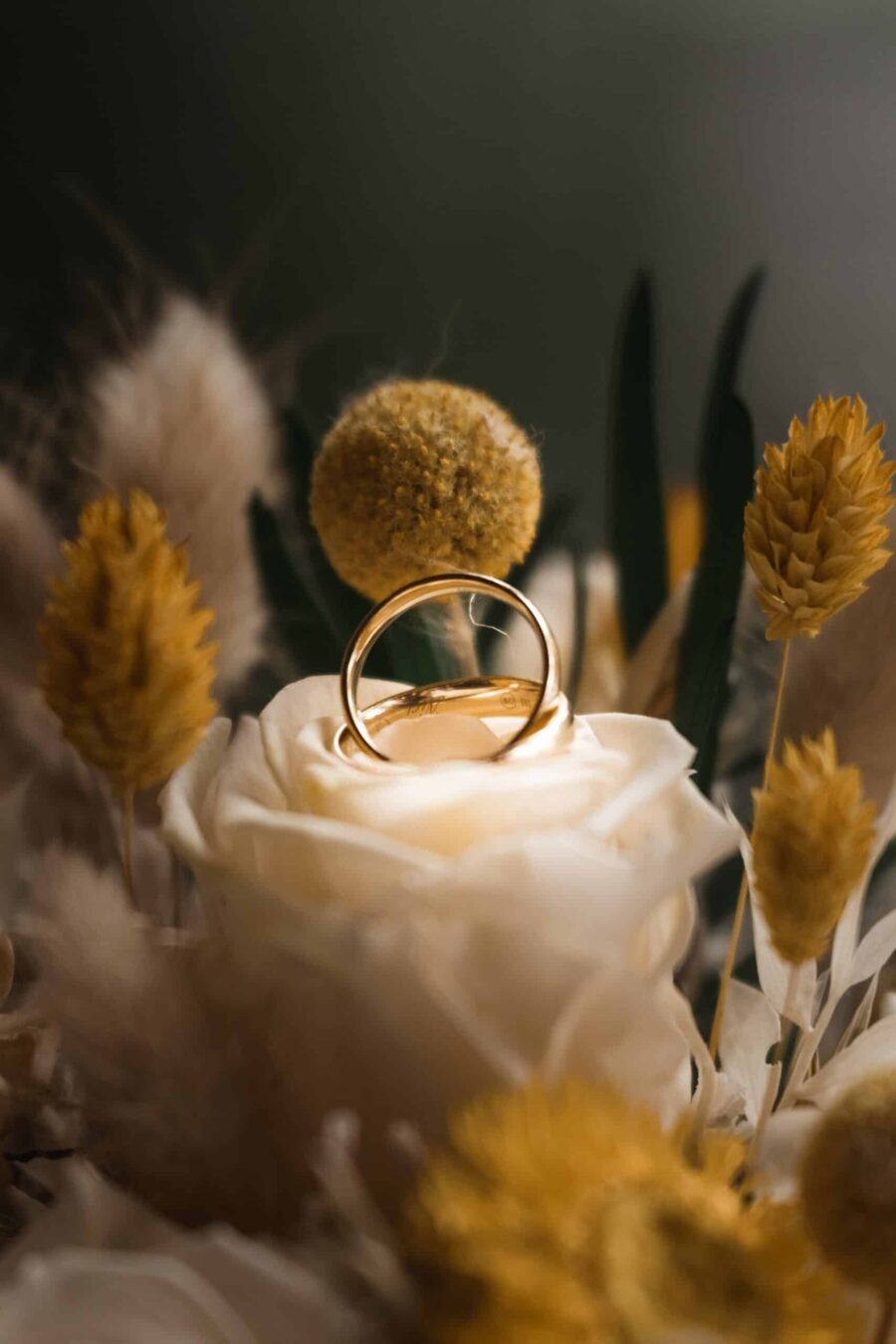 Goldene Eheringe auf rosiger Blume arrangiert