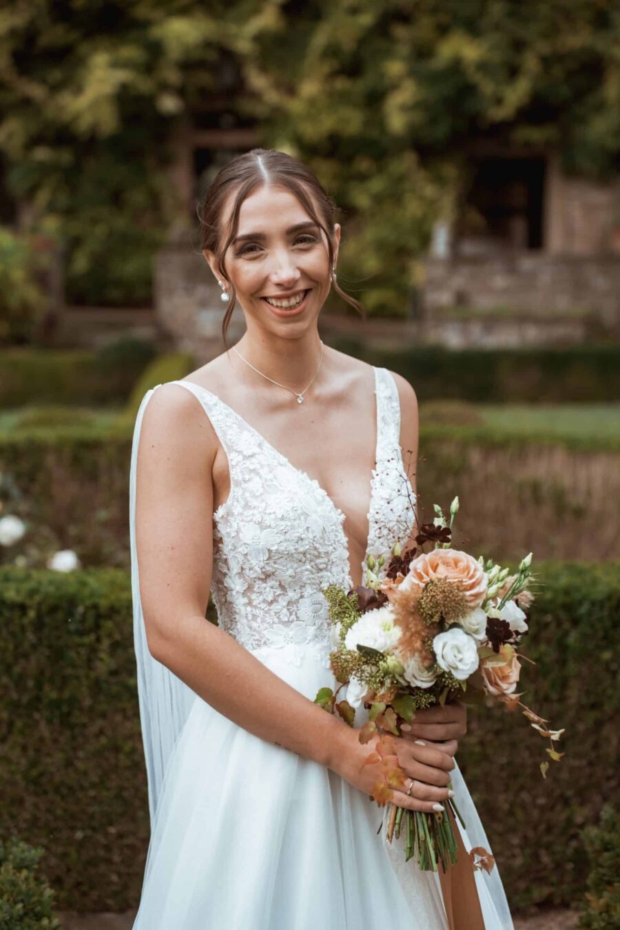 Braut mit Blumenstrauß im Garten.