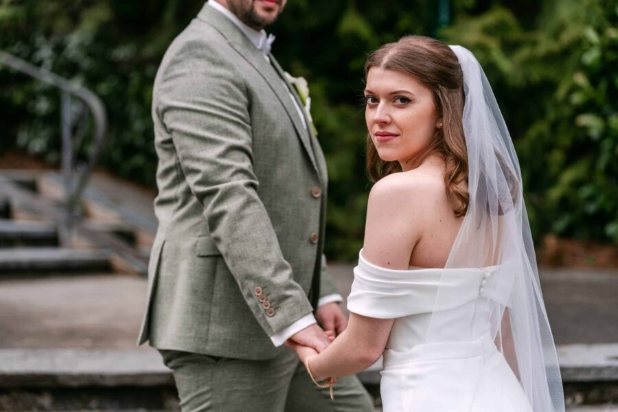 Brautpaar Hand in Hand an Steintreppen im Garten