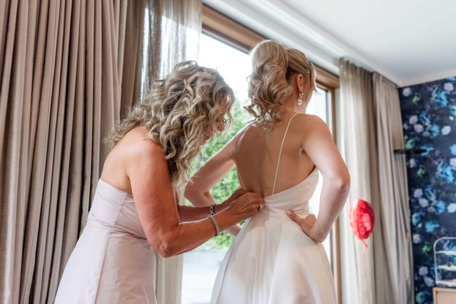 Brautkleid wird von Begleitperson geschlossen