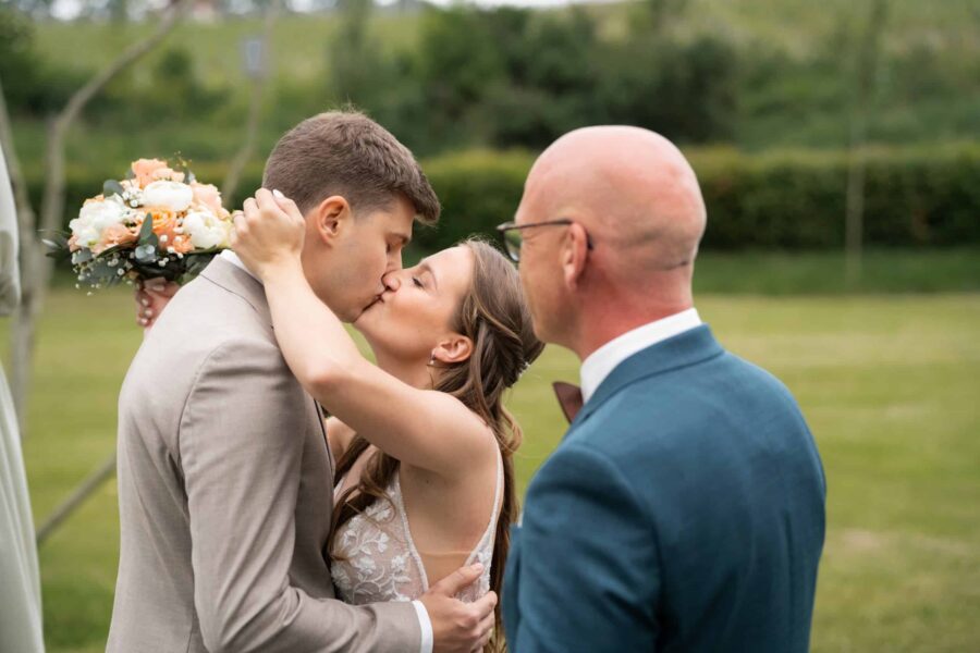 Brautpaar küsst sich im Garten während Trauung