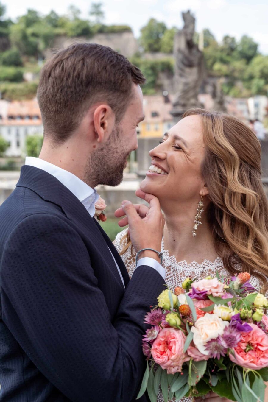 Hochzeit Steinburg Würzburg | Editorial Style & Party | Florian Knusper 14 Brautpaar lächelt sich mit Blumenstrauß an