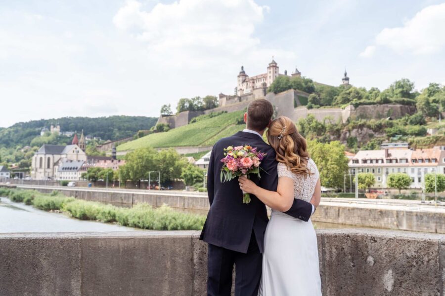 Hochzeit Steinburg Würzburg | Editorial Style & Party | Florian Knusper 109 Brautpaar vor Schlosskulisse mit Blumenstrauß