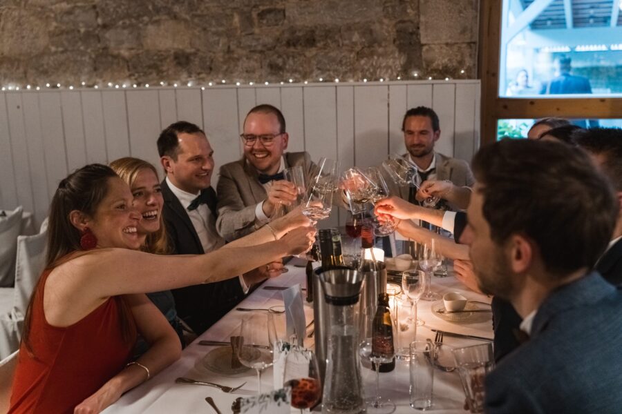 Gäste stoßen mit Sektgläsern am Hochzeitstisch an