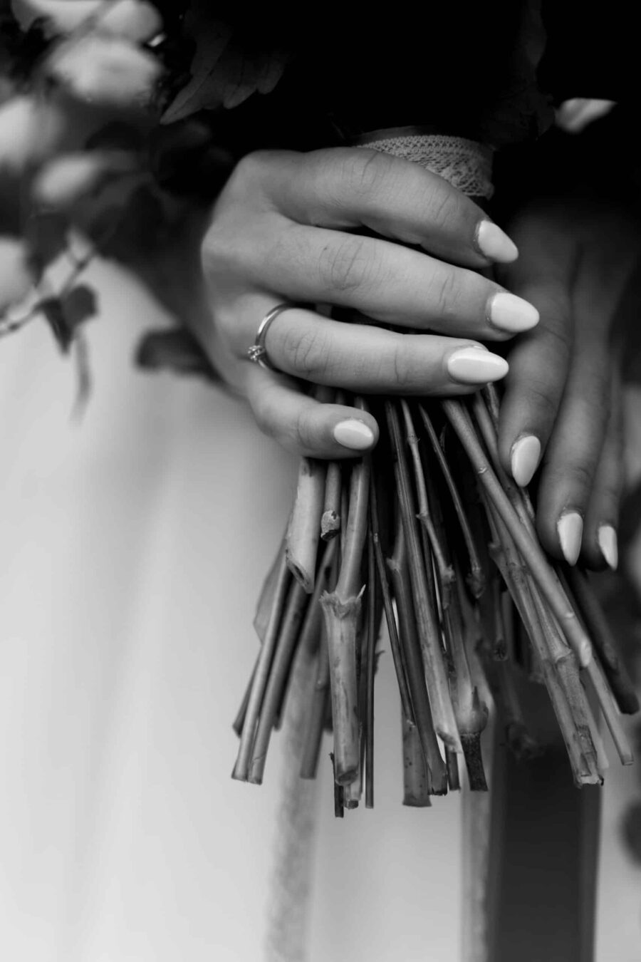 Braut hält Brautstrauß mit Ring an der Hand.