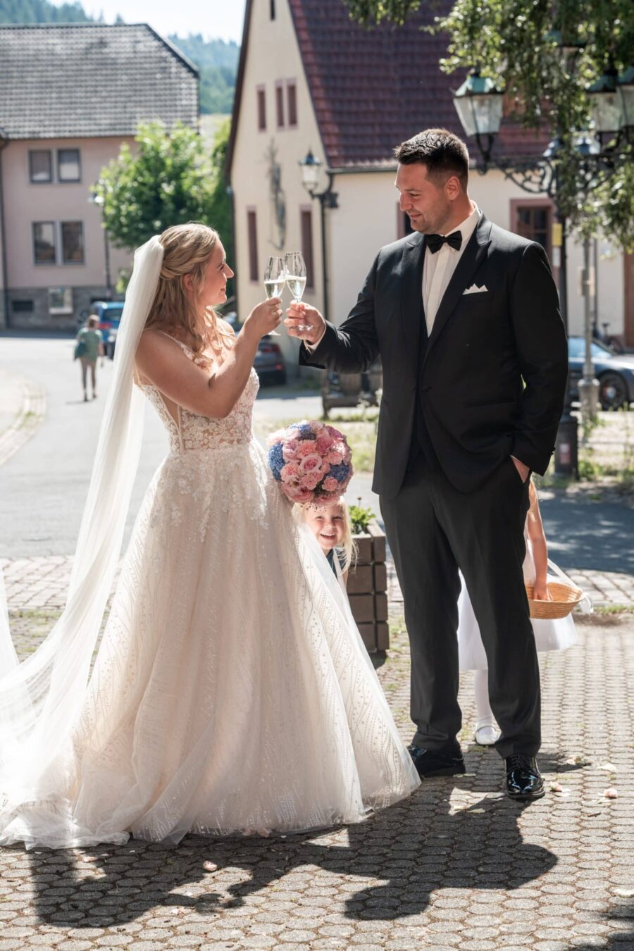 Brautpaar mit Champagner im Dorf.