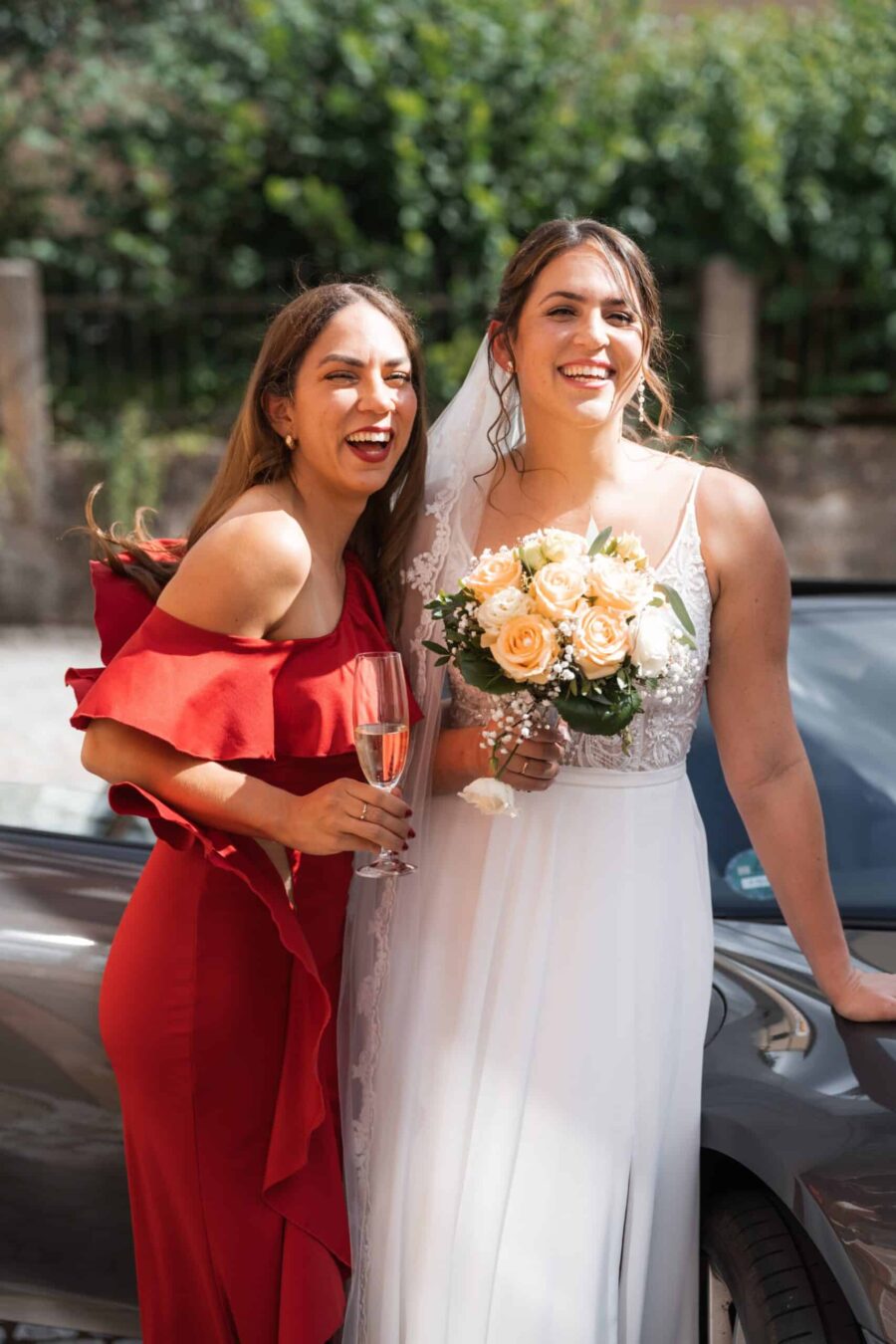 Braut mit Blumenstrauß und Gast in rotem Kleid