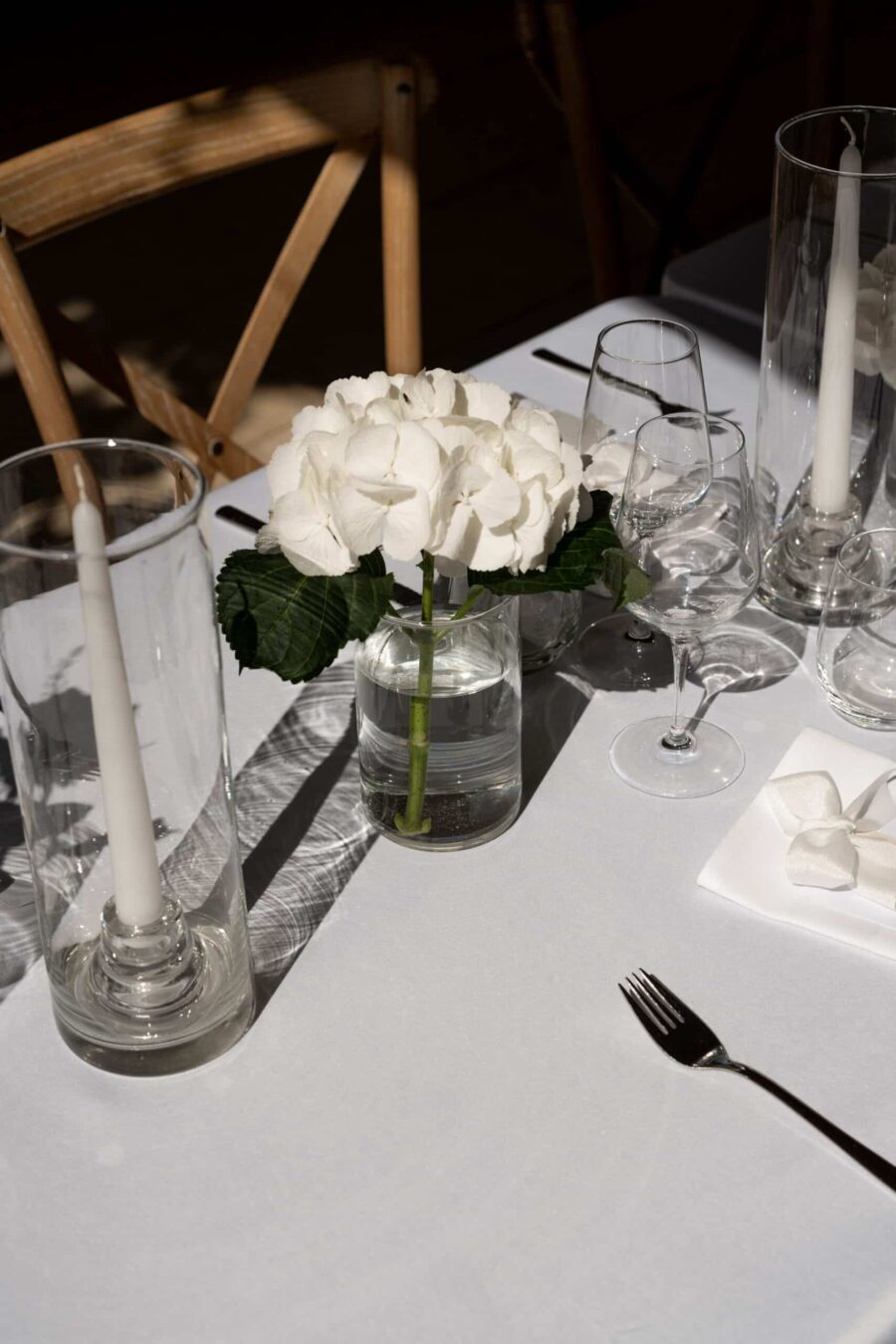 Weiße Tischdekoration mit Blumen und Kerzen.