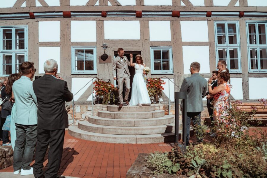 Brautpaar verlässt Location, Gäste applaudieren draußen