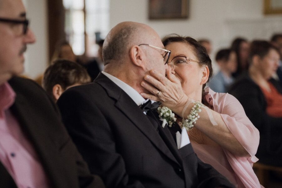 Älteres Paar küsst sich in Hochzeitsgesellschaft.